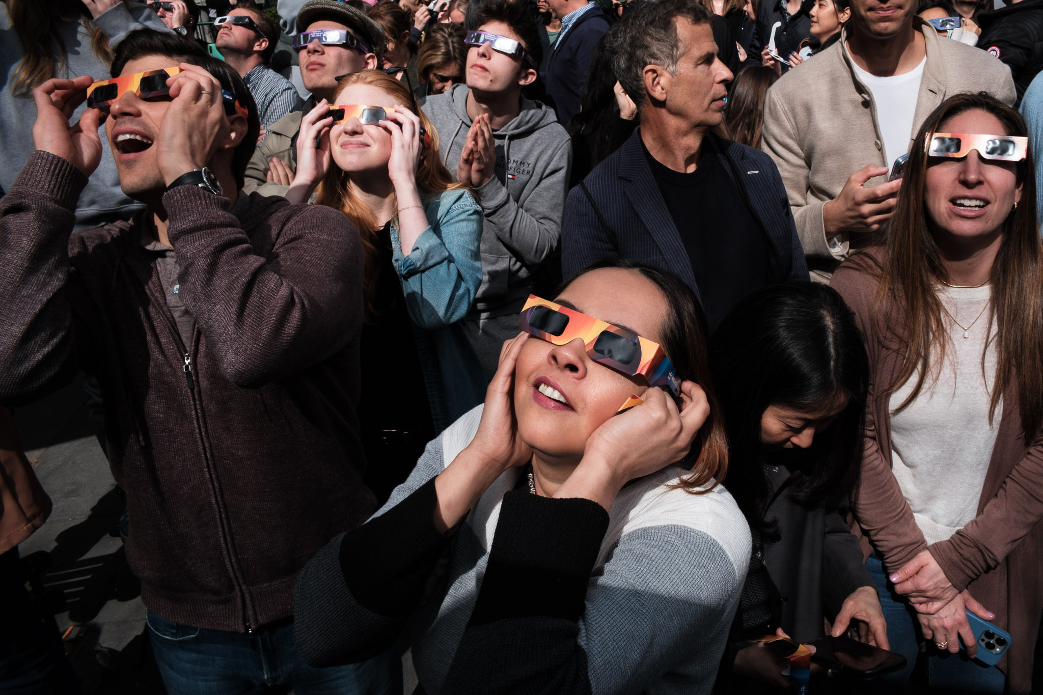 A crowd in New York City watches the April 2024 solar eclipse through protective glasses.